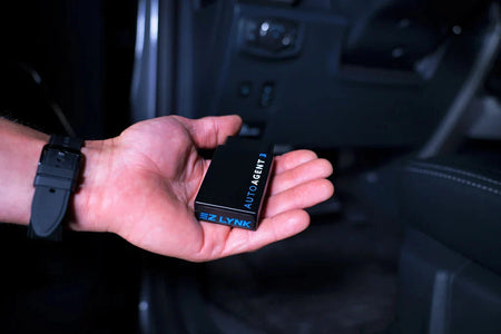 EZ Lynk Auto Agent 3 held in one hand inside a truck cab, showing the device is roughly palm sized